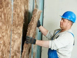 Montér v modré přilbě dává izolaci na stěnu