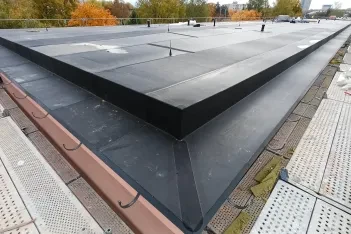 Roh ploché střechy bytového domu v Havířově s novou černou EPDM fólií Prelasti Fleece, po obvodu lešení.